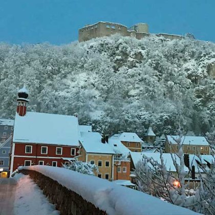 Blick auf die Burgruine von der verschneiten Steinernen Brücke